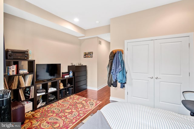 bedroom with dark hardwood / wood-style floors and a closet