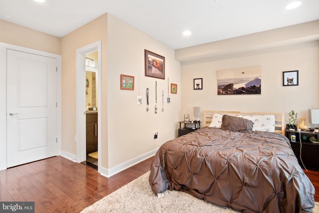 bedroom featuring ensuite bathroom and dark hardwood / wood-style flooring