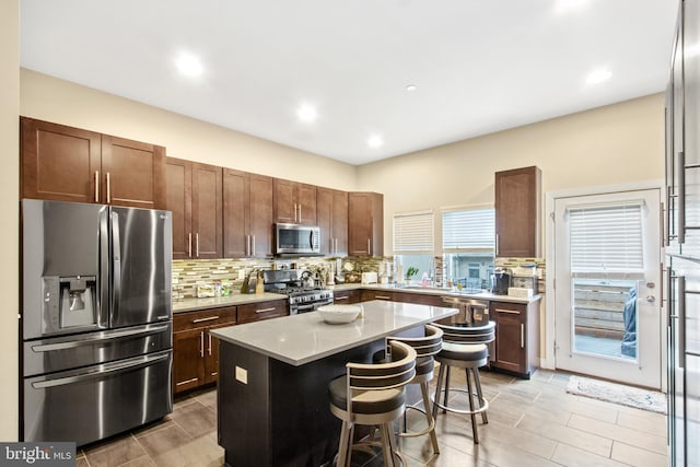 kitchen featuring backsplash, a kitchen island, stainless steel appliances, and a breakfast bar area