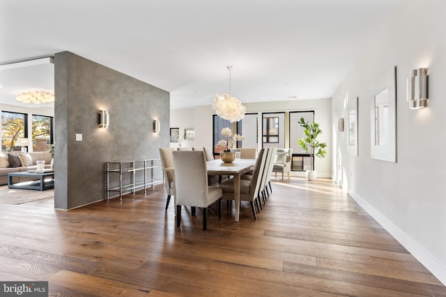 dining area with a notable chandelier, baseboards, and wood finished floors