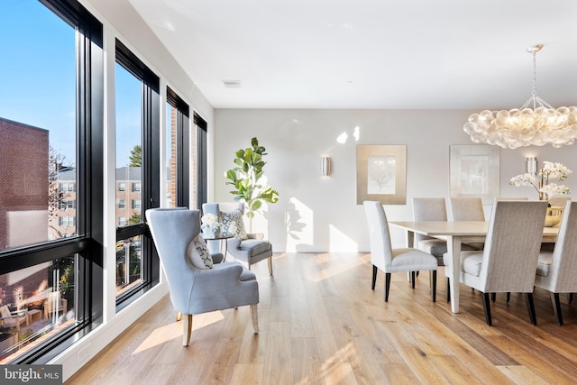 dining space with light wood finished floors, visible vents, and a notable chandelier