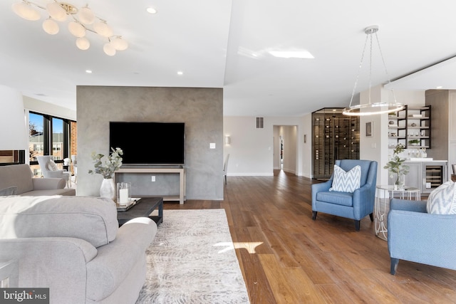 living area with baseboards, visible vents, an accent wall, wood finished floors, and recessed lighting