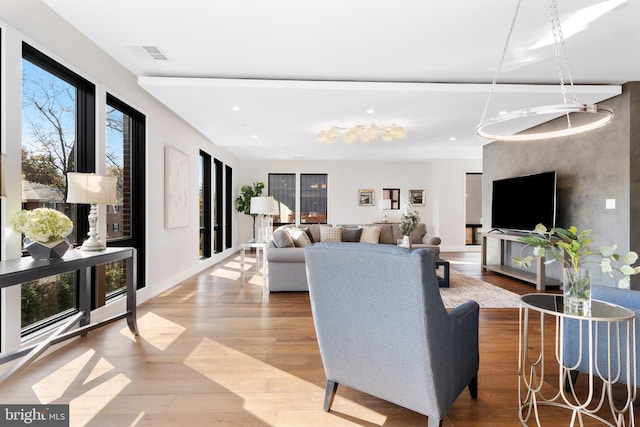 living area with baseboards, light wood-type flooring, visible vents, and recessed lighting