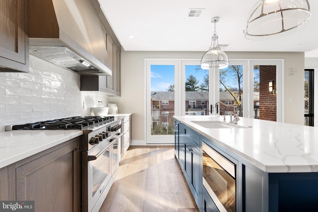 kitchen featuring visible vents, wall chimney exhaust hood, stainless steel appliances, a healthy amount of sunlight, and a sink