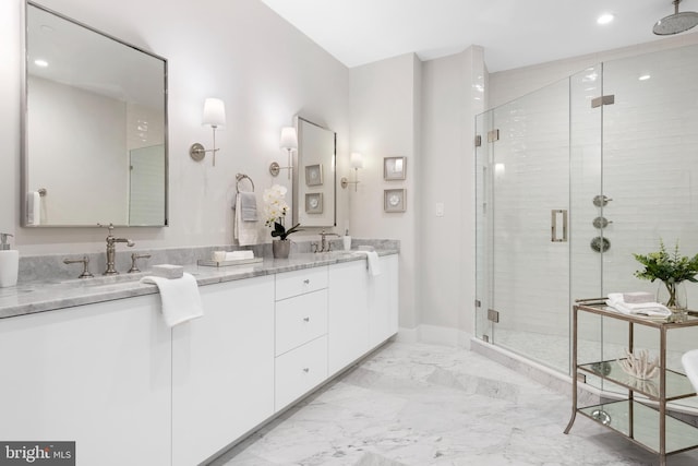 full bath with double vanity, marble finish floor, a shower stall, and a sink