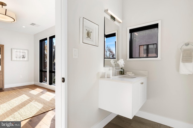 bathroom with vanity, wood finished floors, visible vents, and baseboards