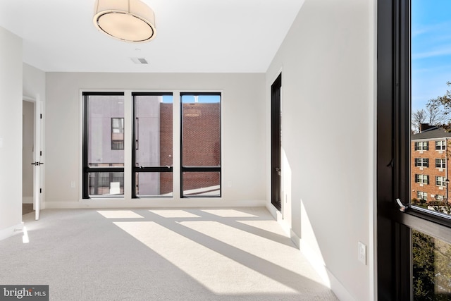 carpeted spare room featuring visible vents and baseboards