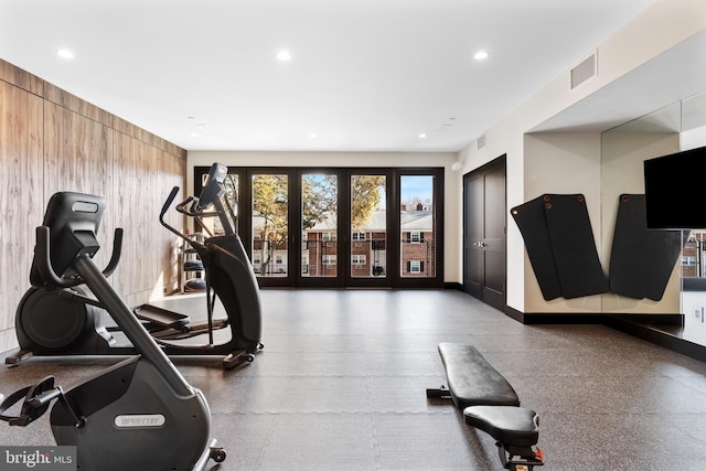 exercise area featuring baseboards, recessed lighting, visible vents, and wooden walls