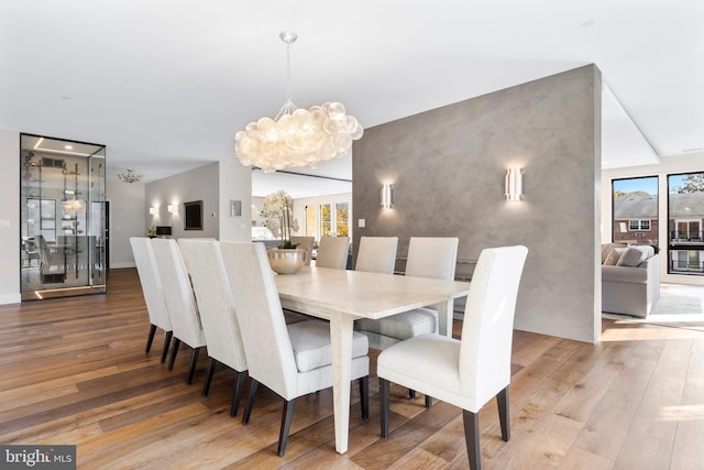 dining area featuring an accent wall, a notable chandelier, and wood finished floors