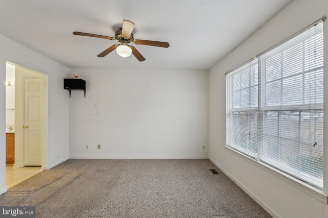 carpeted empty room featuring ceiling fan and electric panel