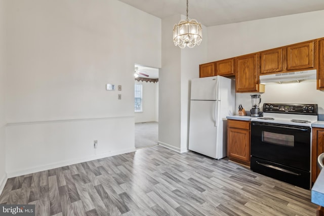 kitchen featuring light hardwood / wood-style flooring, vaulted ceiling, decorative light fixtures, white appliances, and ceiling fan with notable chandelier