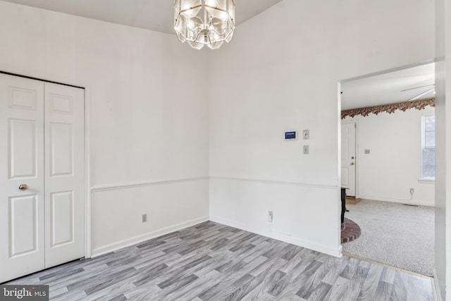 empty room with light wood-type flooring and an inviting chandelier