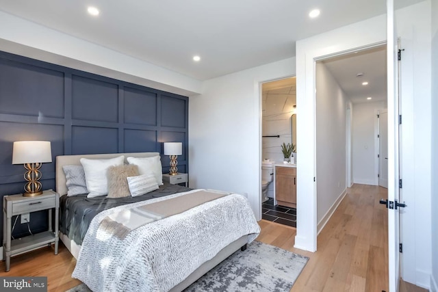 bedroom featuring ensuite bathroom and light hardwood / wood-style flooring