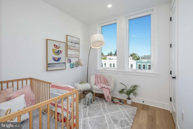 bedroom featuring a nursery area and hardwood / wood-style flooring