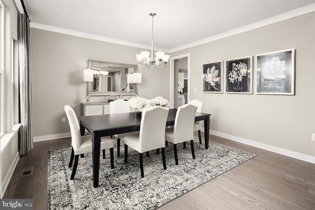 dining room featuring hardwood / wood-style floors, ornamental molding, and an inviting chandelier