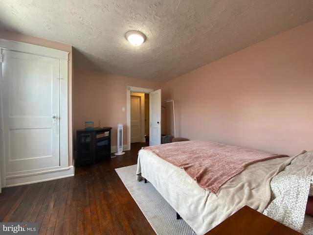 bedroom featuring dark hardwood / wood-style flooring and a textured ceiling