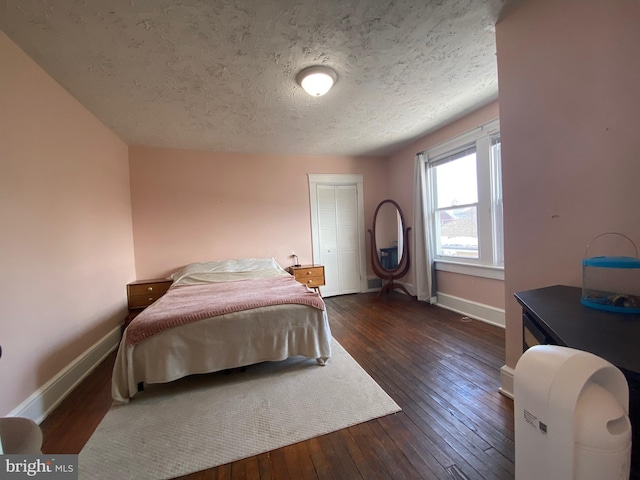 bedroom with dark hardwood / wood-style floors, a textured ceiling, and a closet