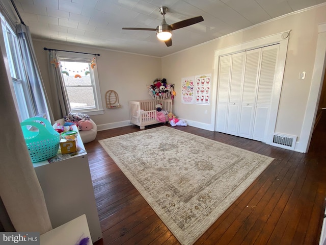 bedroom featuring dark wood-type flooring, ornamental molding, a closet, and ceiling fan