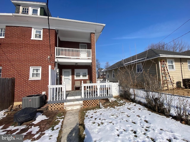 snow covered back of property with a wooden deck and central air condition unit