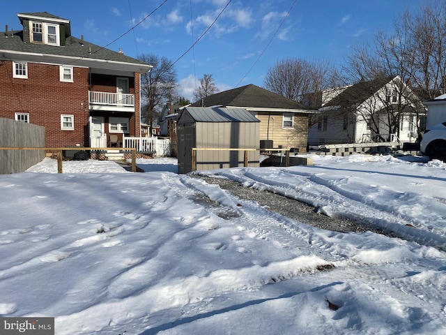 view of snowy exterior featuring a balcony and a shed