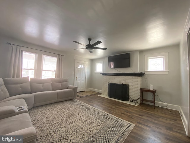 living room with ceiling fan, dark hardwood / wood-style floors, a brick fireplace, and a wealth of natural light