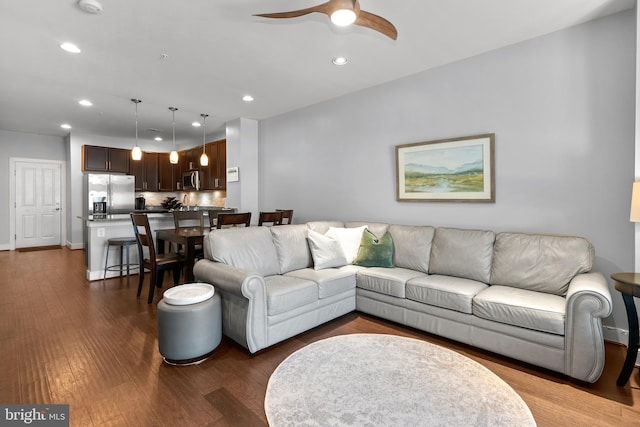 living room featuring ceiling fan and dark hardwood / wood-style flooring