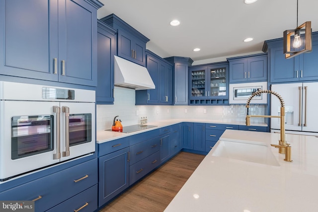 kitchen with blue cabinetry, decorative light fixtures, white appliances, and dark wood-type flooring