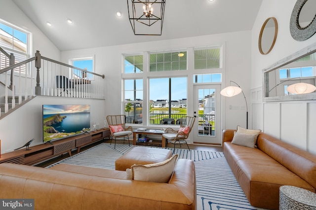 living room with high vaulted ceiling, wood-type flooring, a wealth of natural light, and a chandelier