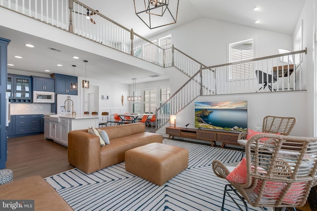 living room with dark hardwood / wood-style flooring, sink, and high vaulted ceiling