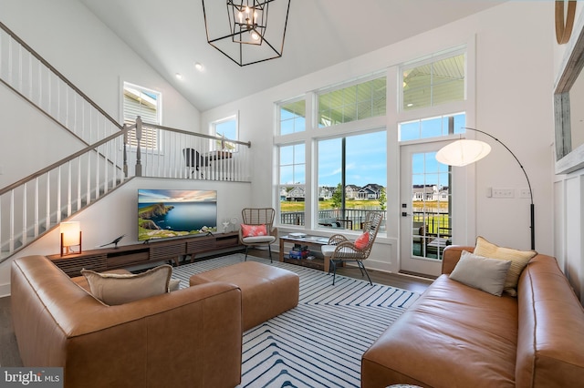 living room featuring wood-type flooring, a towering ceiling, and a notable chandelier