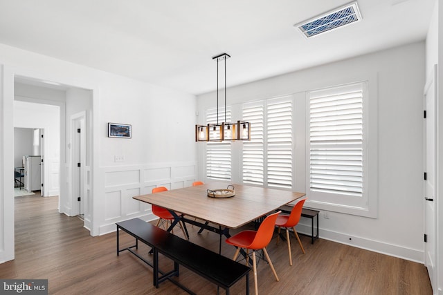 dining area with a wealth of natural light, dark hardwood / wood-style floors, and a notable chandelier