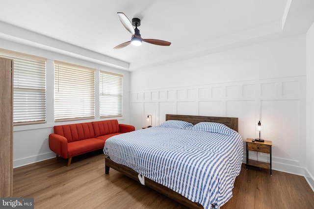 bedroom with a tray ceiling, ceiling fan, and hardwood / wood-style floors