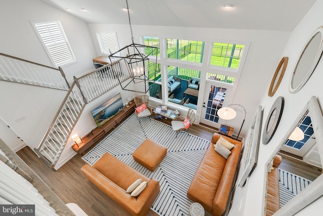 living room featuring a notable chandelier, a healthy amount of sunlight, dark hardwood / wood-style flooring, and a towering ceiling