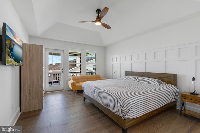 bedroom with ceiling fan, dark hardwood / wood-style floors, access to outside, and a tray ceiling