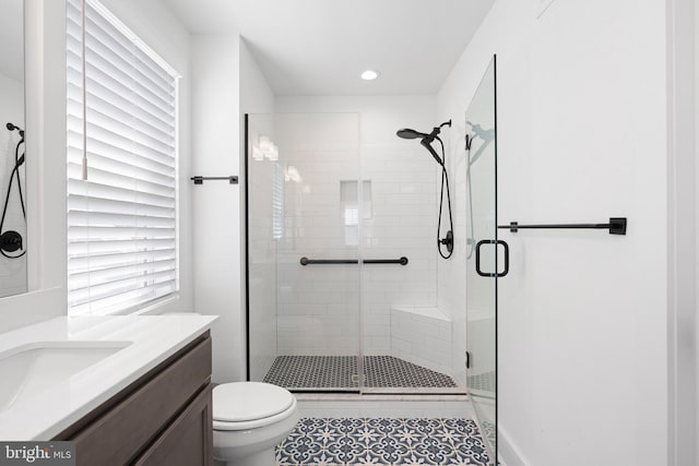 bathroom featuring tile patterned flooring, vanity, a shower with shower door, and toilet