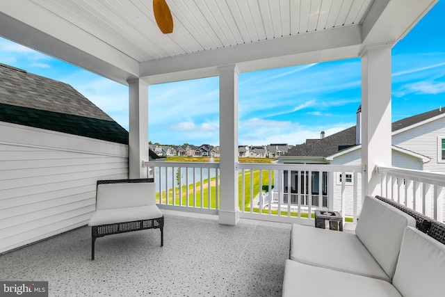 sunroom featuring ceiling fan and a water view