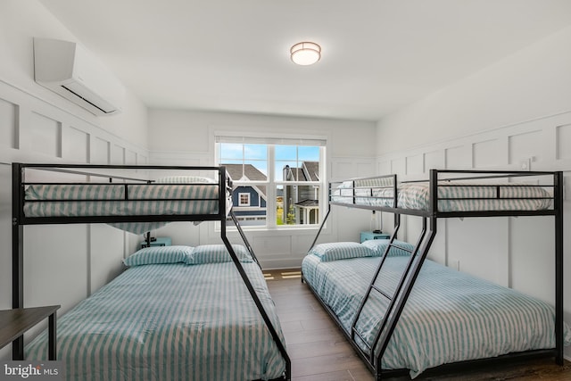 bedroom with dark hardwood / wood-style floors and a wall unit AC