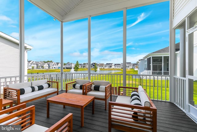 sunroom featuring a water view, a wealth of natural light, and lofted ceiling