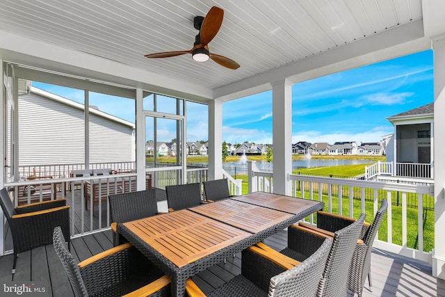 sunroom / solarium with ceiling fan and a water view