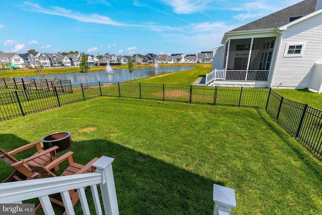 view of yard featuring a sunroom and a water view