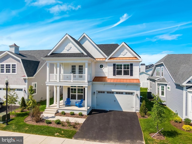 view of front of home with a balcony, covered porch, a front yard, and a garage