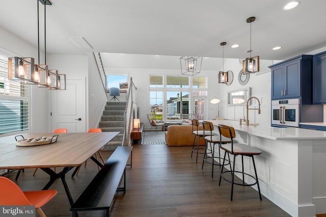 kitchen featuring blue cabinetry, dark hardwood / wood-style flooring, white oven, and hanging light fixtures