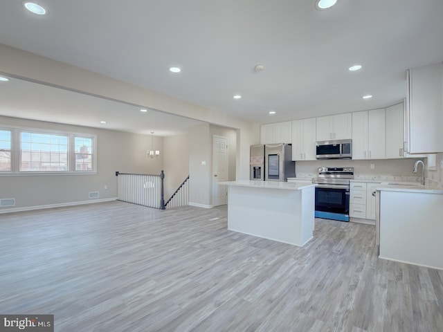 kitchen with light hardwood / wood-style floors, a center island, white cabinetry, and appliances with stainless steel finishes