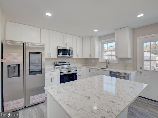 kitchen with a kitchen island, sink, white cabinetry, and stainless steel appliances