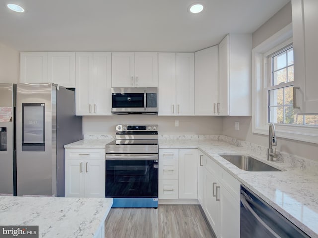 kitchen featuring light stone countertops, sink, white cabinets, and stainless steel appliances