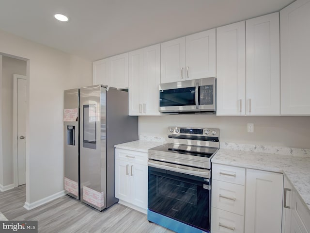 kitchen featuring light stone countertops, white cabinetry, light hardwood / wood-style flooring, and stainless steel appliances