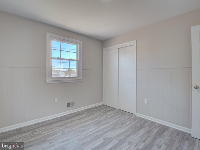 unfurnished bedroom with light wood-type flooring and a closet