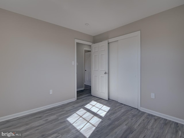 unfurnished bedroom with a closet and dark hardwood / wood-style flooring