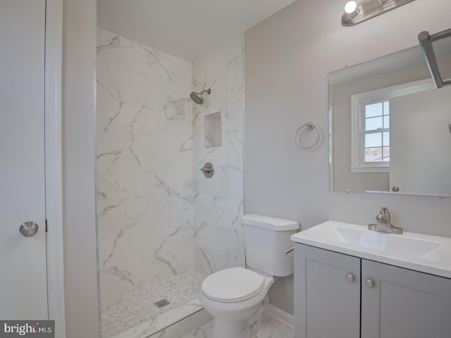 bathroom featuring a tile shower, vanity, and toilet