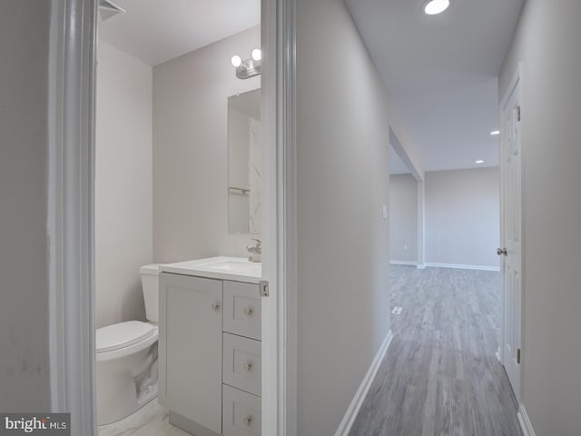 bathroom with wood-type flooring, vanity, and toilet